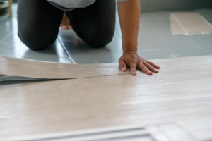 Man kneeling down while installing vinyl flooring